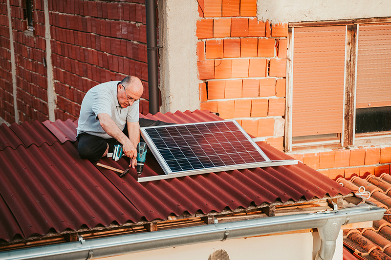 Une personne qui installe des panneaux solaires photovoltaques sur le toit de sa maison.
